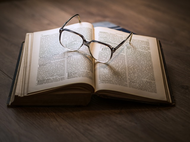 A book, with glasses resting on top.